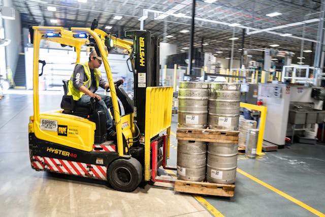 person-driving-yellow-forklift-carrying-metal-barrels