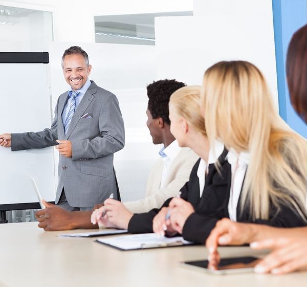 businesspeople looking at businessman explaining in presentation